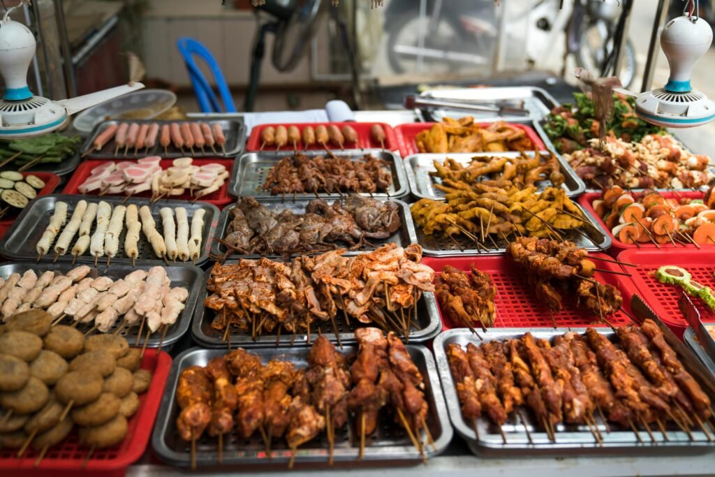 A colorful assortment of grilled street food skewers on display, showcasing various meats and vegetables.